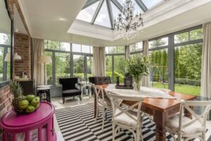 Conservatory & Sunroom ambient lighting - conservatory with chandalier light over a dining table and comfortable seating around the edges